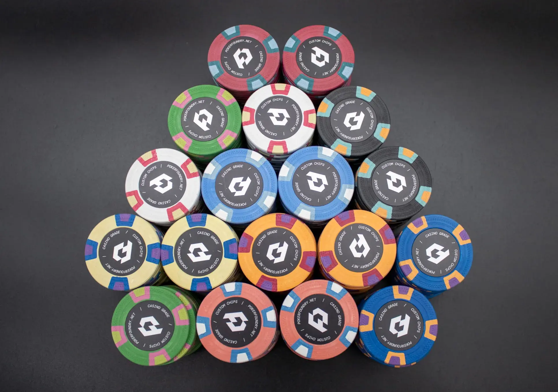 Bevelled-edge clay poker chips in a tight stack highlighting the inlay label and natural matte composite finish