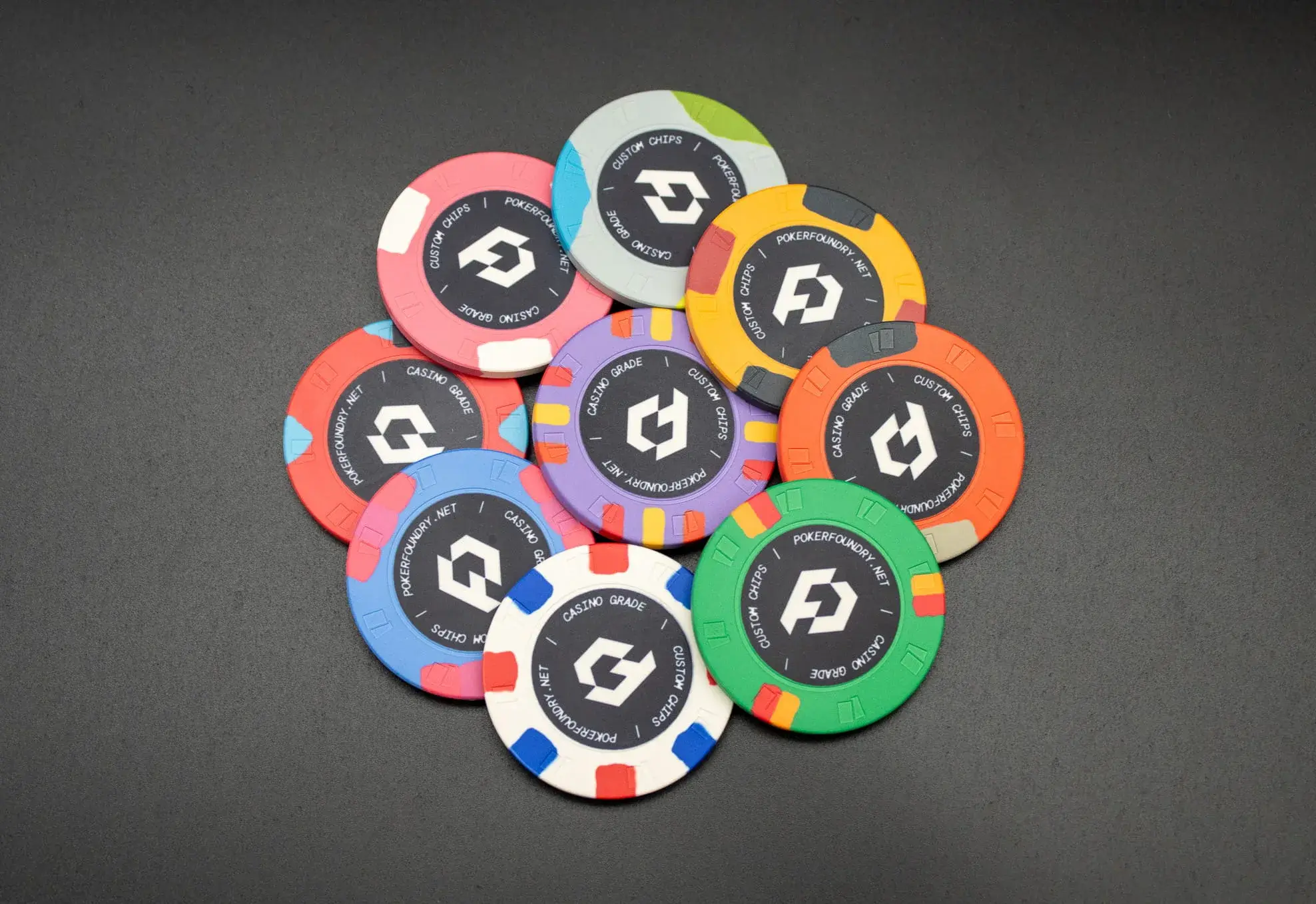Custom ceramic poker chips fanned on a table showing bold club branding and denomination artwork on each face