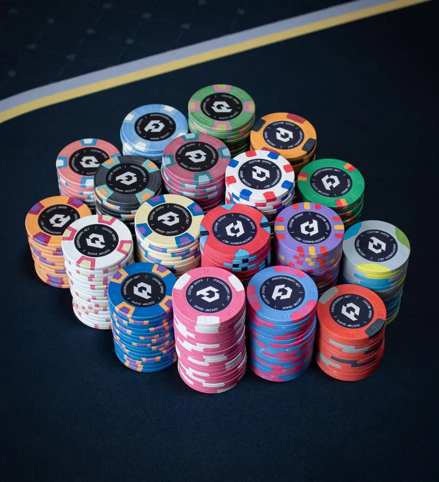 Custom clay and ceramic poker chips on green felt — bevelled-edge clay inlays beside flat-edge ceramic UV-printed chips