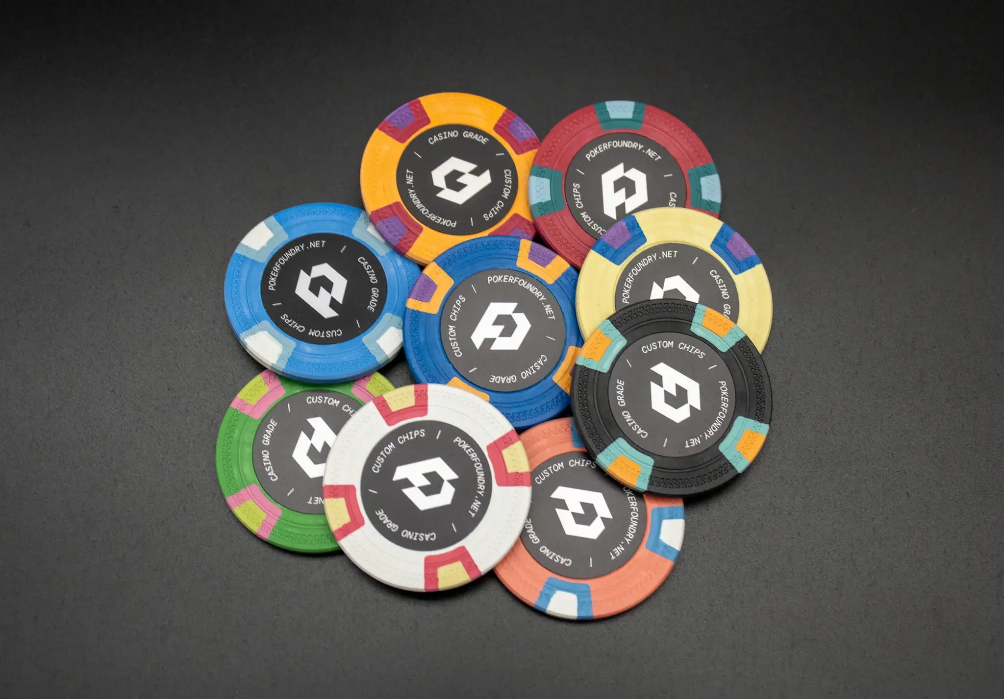 Custom clay poker chips in multiple denominations with printed inlay centres and textured composite bodies