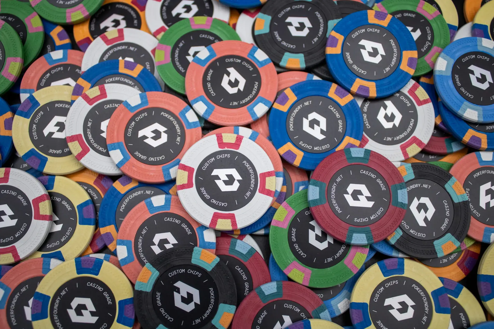 Stacks of casino-weight clay composite chips on poker felt with bevelled rims and geometric edge embossing