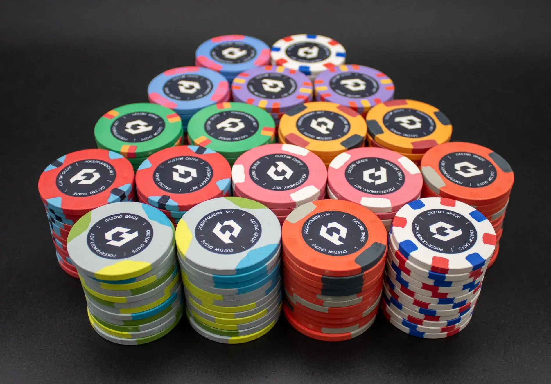 Full set of professional 10g ceramic poker chips photographed with consistent custom artwork across denominations
