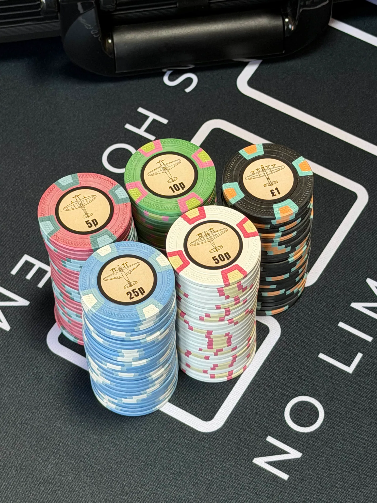 Finished custom clay poker chips with WWII aircraft labels spread on a home poker table